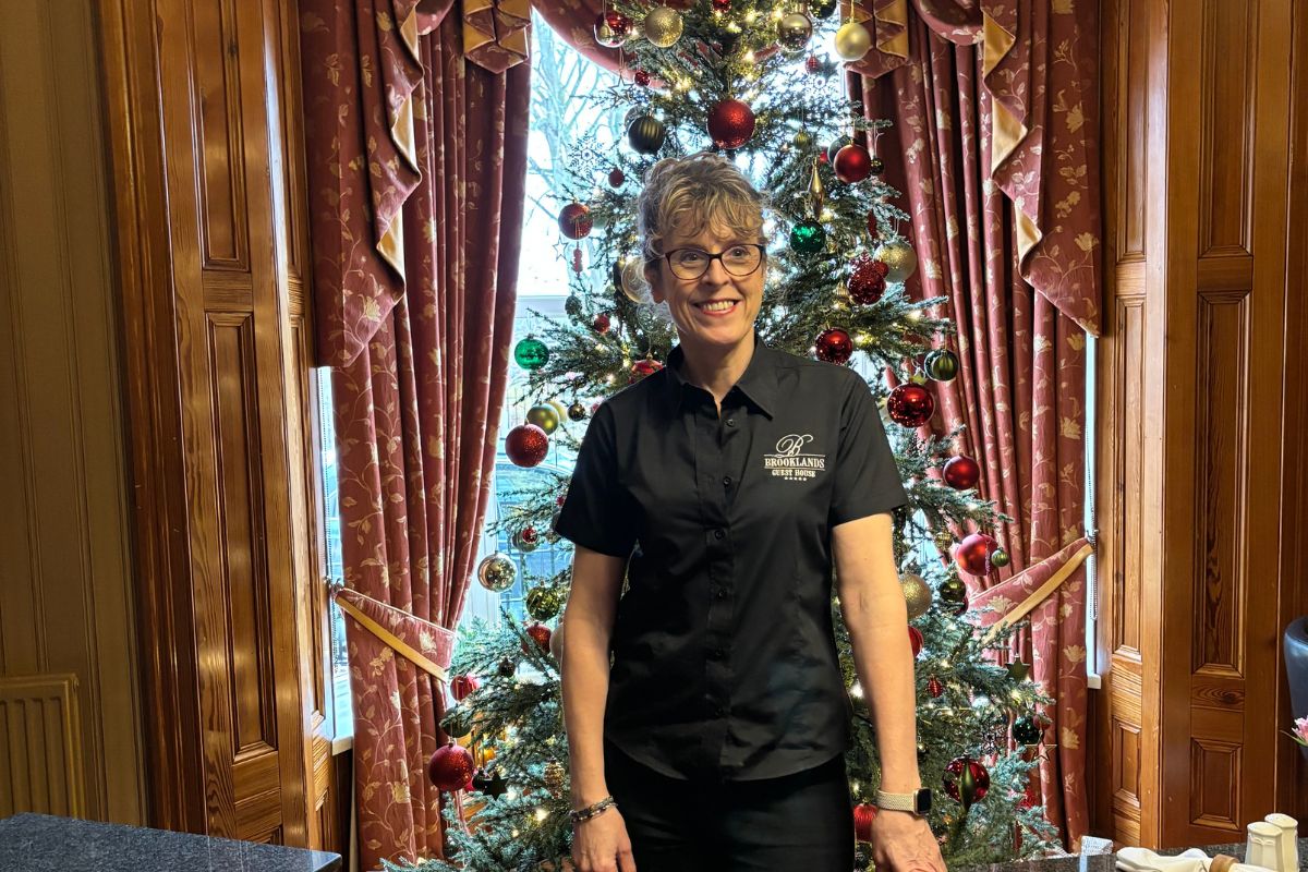 Owner of Brooklands of Guest House, standing in front of a Christmas tree